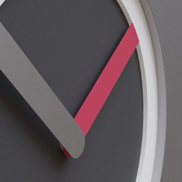 Close-up of the KAM Bloom wall clock showing a dark dial, pale circular ring and pink hand