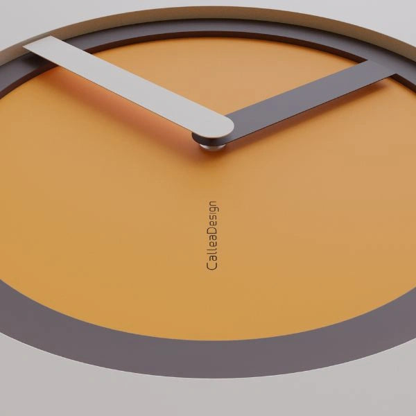 Close-up of the KAM Sole wall clock with a golden dial, dark ring and pale hands