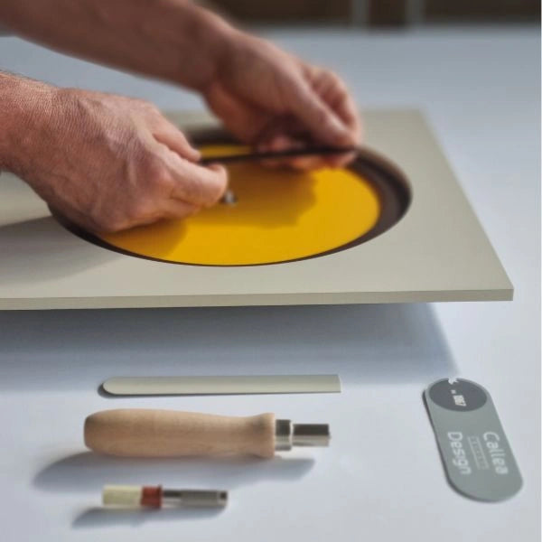 Hands assembling the colourful KAM Sole wall clock in the atelier