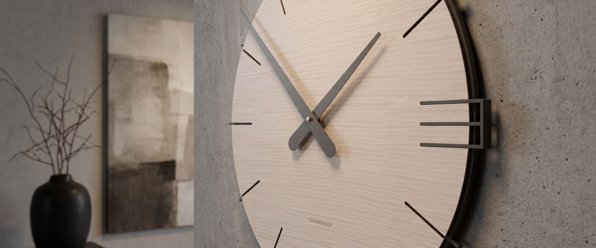 Nahaufnahme einer CalleaDesign Wanduhr mit hellem Holzzifferblatt und dunklen Zeigern in einem modernen Raum